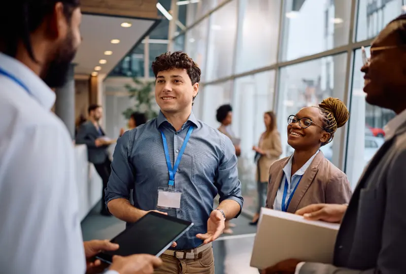 7 A group of professionals wearing name tags engage in conversation in a modern office hallway.