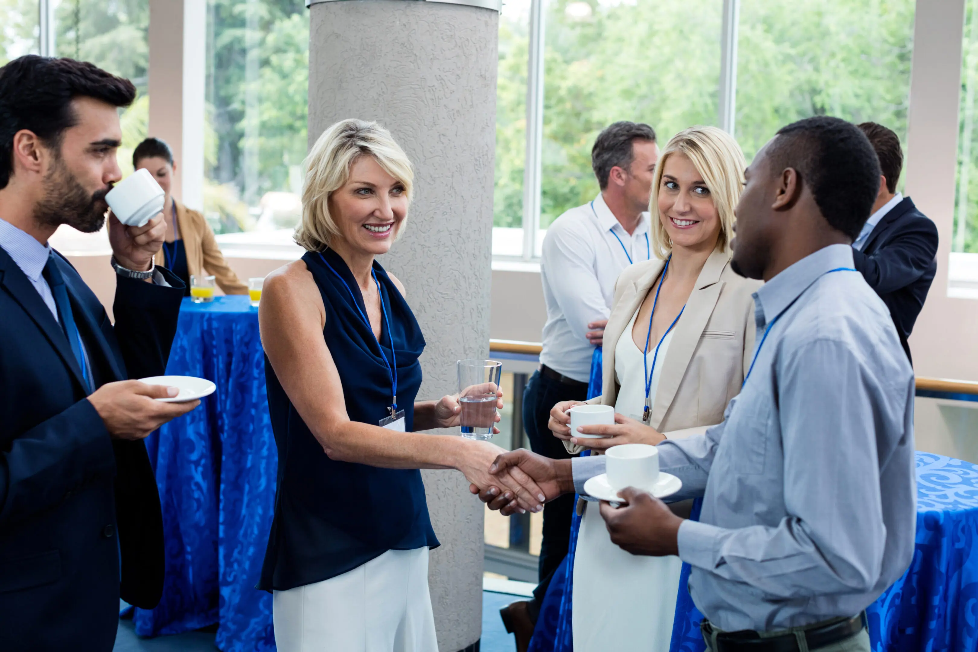 Business executives interacting with each other while having coffee A group of people standing around each other.